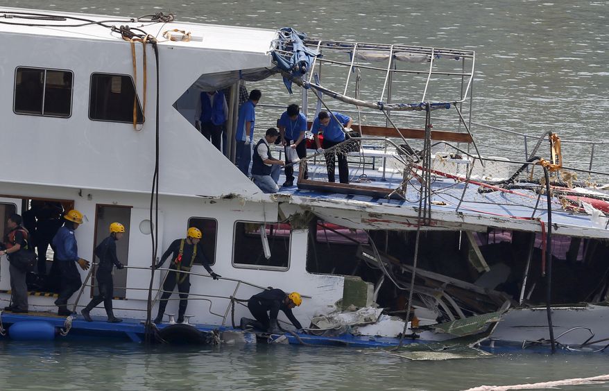 Firemen and police officers investigate on a salvaged boat that sank after colliding with a ferry near Lamma Island, off the southwestern coast of Hong Kong Island, on Wednesday, Oct. 3, 2012. (AP Photo/Kin Cheung)