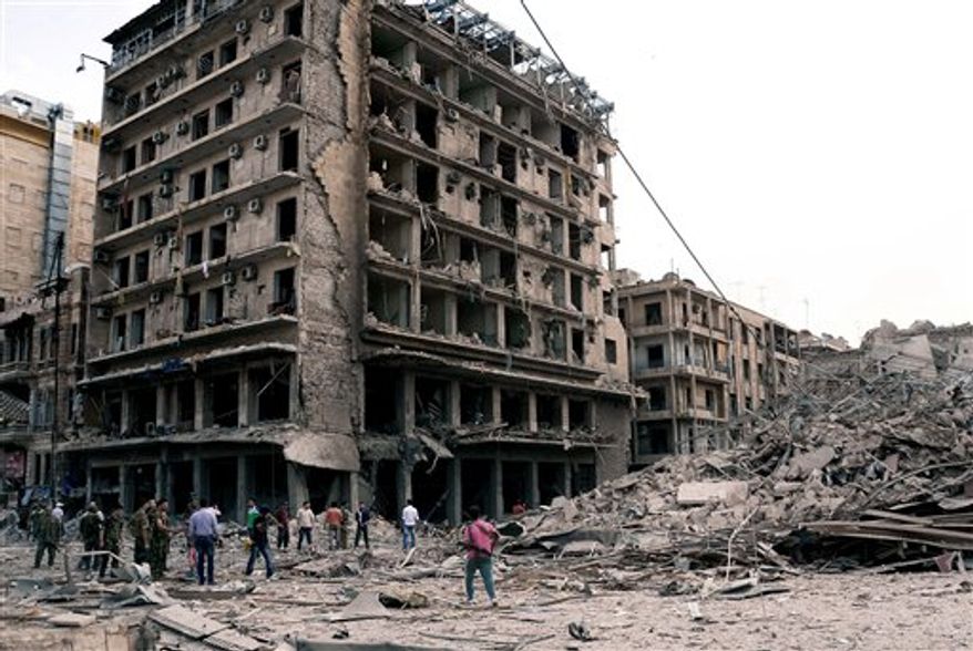 In this photo released by the Syrian official news agency SANA, Syrian security officers gather at the scene in front of destroyed buildings where triple bombs exploded at the Saadallah al-Jabri square, in Aleppo city, Syria, Wednesday Oct. 3, 2012. Three powerful explosions rocked the main square in a government-controlled central district of Aleppo on Wednesday, the Syrian state-run TV said. (AP Photo/SANA)