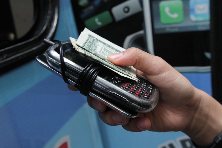 A student hands over two electronic devices and payment of a dollar for each at the Pure Loyalty Electronic Device Storage truck parked near the Washington Irving educational complex in New York on Sept. 27, 2012. Cellphones are banned in all New York City public schools, but the rule is widely ignored except in schools with metal detectors. Outside those schools, entrepreneurs park trucks where students drop off electronic devices before class and get them back at the end of the day. (Associated Press)