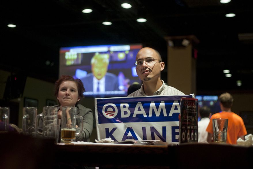Alyssa Boffey, left, and Tony Robinson, right, watch the first presidential debate between President Obama and Republican nominee Mitt Romney during a watch party put on by the Arlington Young Democrats and the Arlington County Democratic Committee at Bailey's Pub in Ballston Common Mall, Ballston, Va., Wednesday, Oct. 3, 2012. (Craig Bisacre/The Washington Times)