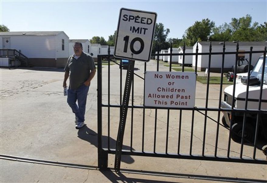 James Womack, director of Hand Up Ministries, walks through the gate which has a sign prohibiting women or children inside the community, in Oklahoma City, Wednesday, Oct. 3, 2012. Hand Up Ministries is a non profit faith-based organization that offers help to men and women coming out of the prison system to re-enter society. The grounds currently house 150 sex offenders and 7 other felons. (AP Photo/Sue Ogrocki)