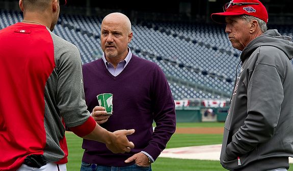 Washington Nationals general manager Mike Rizzo, center, and manager Davey Johnson, right, talk with a player during a workout session on the field at Nationals Park on Tuesday, Oct. 9, 2012. On Wednesday, they play the St. Louis Cardinals at home. (Barbara L. Salisbury/The Washington Times)