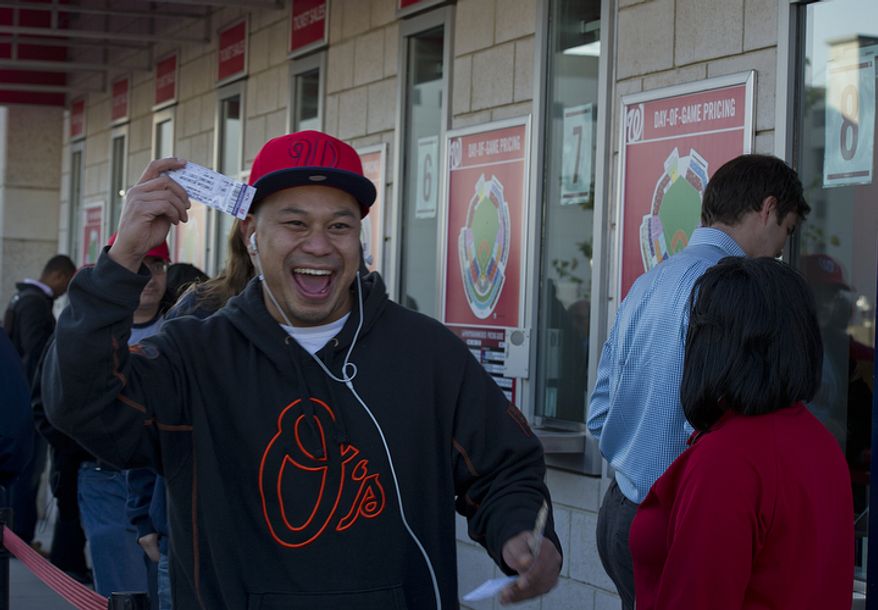 David Chheng of Herndon, Va. smiles as he holds up his ticket for the first home playoff game at Nationals Park on Wednesday, Oct. 10, 2012. He got to the stadium at 8:35 a.m. and paid $30 for the standing-room-only seat. He says he also follows the Orioles (thus the sweatshirt) and would love to see the two teams play each other. (Barbara L. Salisbury/The Washington Times)