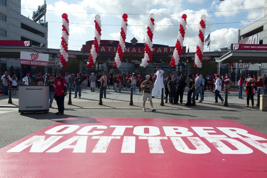 Fans gather outside Nationals Park in Washington on Wednesday, Oct. 10, 2012, for the Nationals' first home playoff game. The words "October Natitude" have been painted on the street in front of the center-field gate. (Barbara L. Salisbury/The Washington Times)