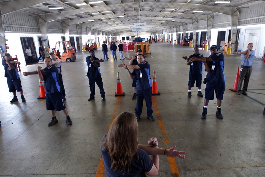 **FILE** Wellness coach Kara Whitcomb (front center) leads truckers in a stretching regime before their driving shifts start at Con-way Freight in Garland, Texas, on July 11, 2012. (Associated Press)