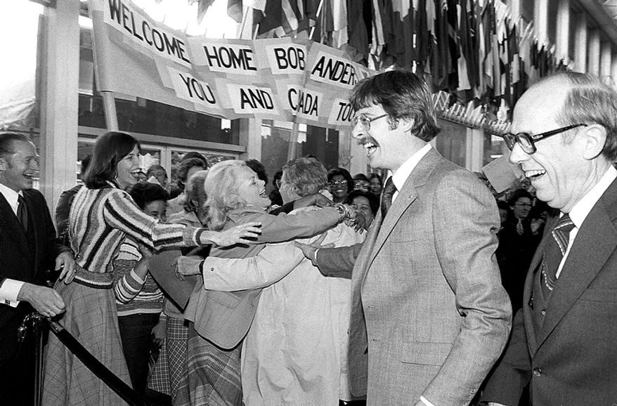 The crowd gathered at the State Department reaches out to embrace Robert G. Anders, in white raincoat at center, one of the six diplomats that the Canadians helped spirit out Teheran last weekend, shown Feb. 1, 1980 in Washington. At right is Henry L. Schatz, one of the six who spent three months in hiding in the Canadian Embassy in Iran. (AP Photo)