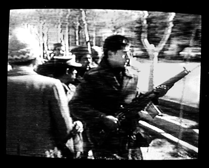 A man carries an assault rifle during the storming of the U.S. Embassy in downtown Teheran, Iran, Feb. 14, 1979. Ambassador William Sullivan and 101 other Americans were taken hostage. Photo was made from a television monitor showing CBS-TV. (AP Photo/Suzanne Vlamis)