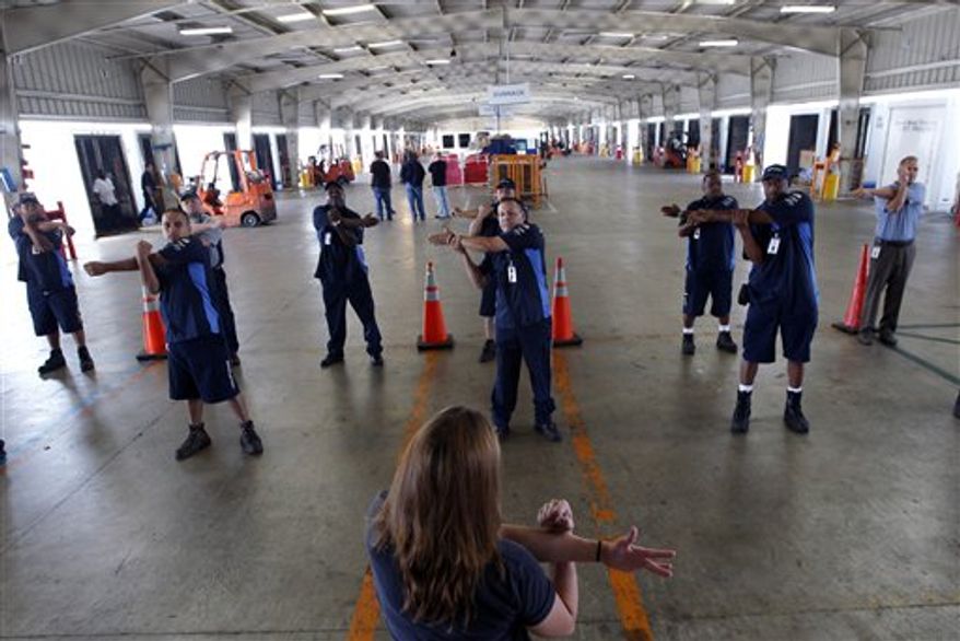 In this July 11, 2012, photo, wellness coach Kara Whitcomb, front center, leads truckers in a stretching regime before their driving shifts start at Con-way Freight in Garland, Texas. From trucking companies embracing wellness and weight-loss programs to gyms being installed at truck stops, momentum has picked up in recent years to help those who make their living driving big rigs get into shape. (AP Photo/LM Otero)