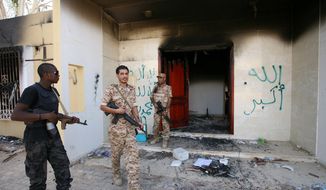 **FILE** Libyan military guards inspect the burnt-out buildings at the U.S. Consulate in Benghazi, Libya, during a visit by Libyan President Mohammed el-Megaref to express sympathy for the death of American ambassador to Libya Chris Stevens and his colleagues in the Sept. 11, 2012, attack on the consulate. (Associated Press)