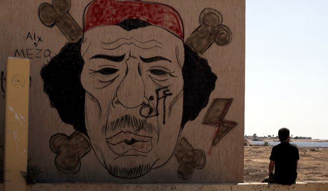 **FILE** A Libyan man sits Sept. 20, 2012, near a mural of Moammar Gadhafi in Benghazi, Libya. (Associated Press)