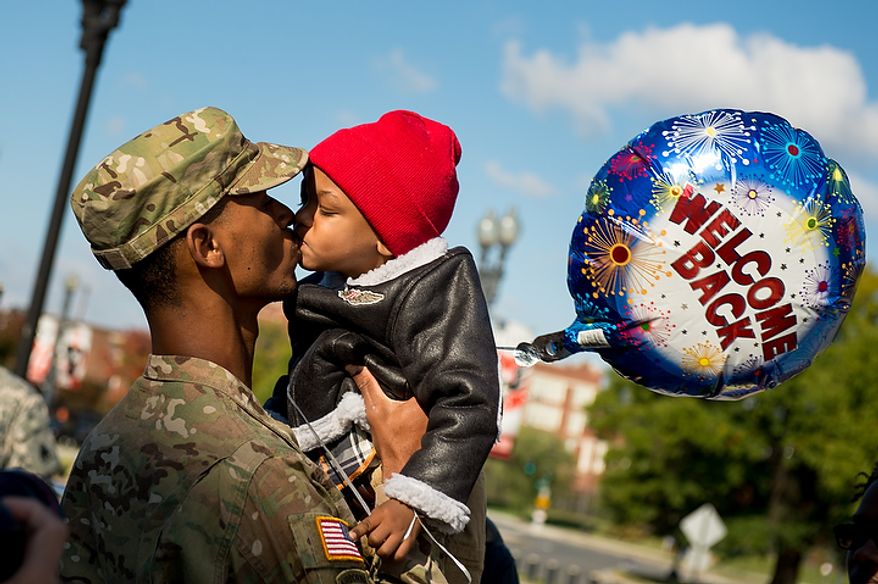 Spc. Marques Turpin, one of the 70 D.C. Army National Guard soldiers with the 273rd military police company returning from Bagram Air Base, Afghanistan after 10 months kisses his son Josiah, 2, following a welcome home ceremony held in front of the D.C. Armory, Washington, D.C., Tuesday, October 16, 2012. (Andrew Harnik/The Washington Times)
