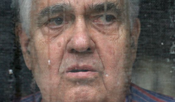 In this Sept. 15, 2011 photo, Bill Ricker, 74, looks out the screen door of his trailer home on a rainy day, in Hartford, Maine. Ricker, who has two college degrees, has worked as an electronics repairman, a pastor and a TV cameraman. He and his first wife had seven children. Now he receives food stamps and heating fuel assistance and gets donations from a local food pantry. (AP Photo/Robert F. Bukaty)