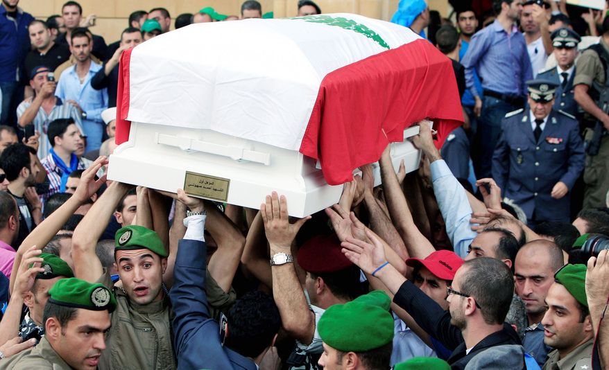 Honor guards carry the coffin, which is wrapped in the Lebanese flag, of Brig. Gen. Wissam al-Hassan during the funeral procession at Martyrs Square in Beirut on Sunday. Gen. al-Hassan was killed by a car bomb on Friday. (Associated Press)