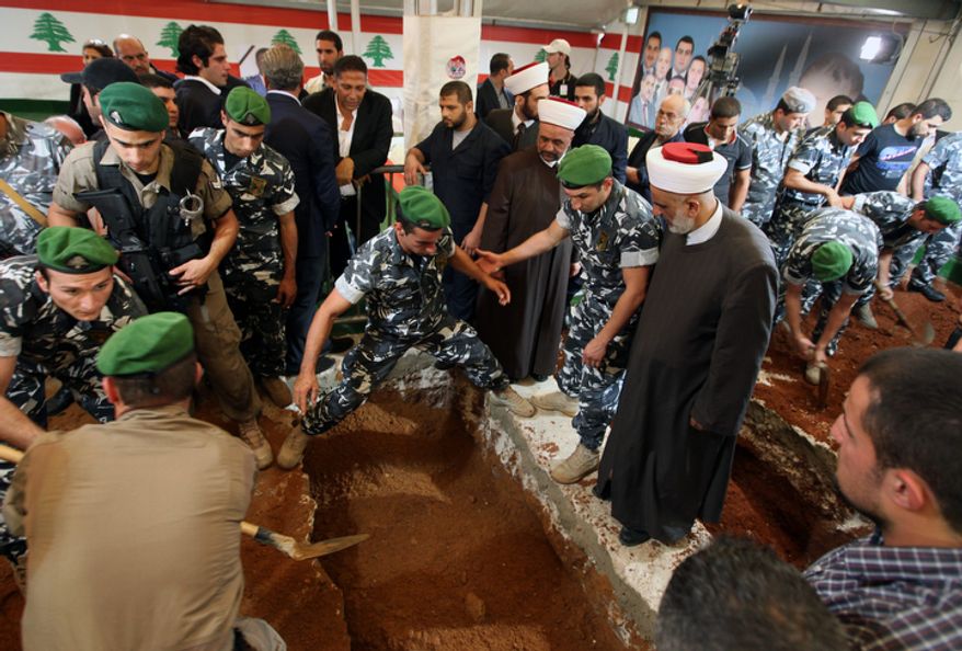 A Lebanese honor guard buries Brig. Gen. Wissam al-Hassan and and his bodyguard, Ahmad Sahyouni, who were assassinated on Friday by a car bomb, at Martyrs' Square in Beirut, Lebanon, Sunday, Oct. 21, 2012. Lebanese soldiers fired guns and tear gas to push back hundreds of protesters who broke through a police cordon and tried to storm the government headquarters in Beirut. The enraged crowd came from the funeral of a top Lebanese intelligence official assassinated in a massive car bombing.(AP Photo/Bilal Hussein)