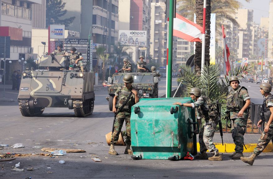 Lebanese Army soldiers remove garbage containers used as a roadblock in a neighborhood after overnight clashes between Sunni and Shiite gunmen in Beirut on Monday. Troops began a big operation in the capital aiming to open all closed roads and to force gunmen out of the streets. (Associated Press)