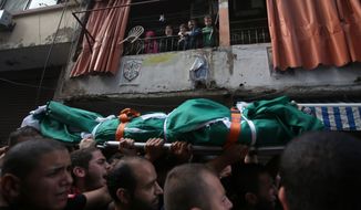 A Palestinian family (top) watches mourners Oct. 23, 2012, carry the body of Palestinian Ahmad Queider, 20, during a funeral procession in the Sunni neighborhood of Tarik al-Jadida in Beirut. The man was killed the day before as he rode his motorcycle during an exchange of gunfire between Lebanese troops and gunmen. (Associated Press)