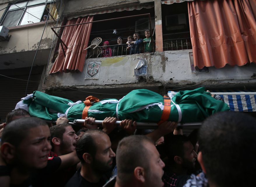 A Palestinian family (top) watches mourners Oct. 23, 2012, carry the body of Palestinian Ahmad Queider, 20, during a funeral procession in the Sunni neighborhood of Tarik al-Jadida in Beirut. The man was killed the day before as he rode his motorcycle during an exchange of gunfire between Lebanese troops and gunmen. (Associated Press)