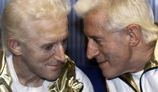 ** FILE ** TV host Jimmy Savile (right) poses for photographers with a wax model at Madame Tussauds museum in London in 1986. (AP Photo/John Redman)