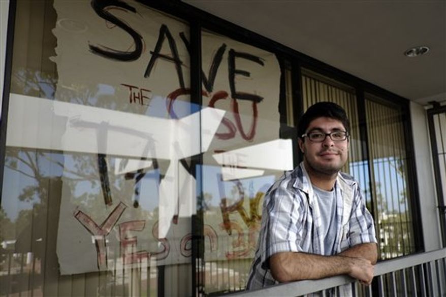 In this Friday, Oct. 19, 2012 photo, graduate student Pedro Ramirez is photographed in front of a Proposition 30 sign on the campus of California State University, Long Beach in Long Beach, Calif. Proposition 30 includes a temporary quarter-cent increase in the statewide sales tax and higher income taxes on those who make more than $250,000 a year. "We tell them if you don't vote you're literally going to be voting for a tuition increase," said Mr. Ramirez, a graduate student at Cal State-Long Beach who is working to rally student support for the ballot measure. (AP Photo/Jae C. Hong)