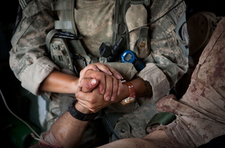 ** FILE ** U.S. Army chief Spc. Jenny Martinez holds the hand of an injured U.S. Marine who was wounded in an IED strike in June, 2011. (AP Photo/Anja Niedringhaus)