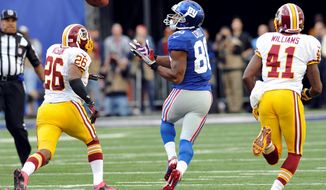 Wide receiver Victor Cruz prepares to gather in a 77-yard touchdown pass as Redskins defensive backs Josh Wilson and Madieu Williams pursue him. (Associated Press)