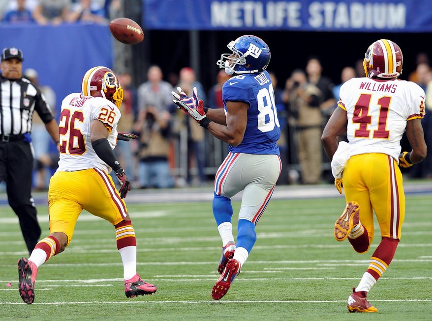 Wide receiver Victor Cruz prepares to gather in a 77-yard touchdown pass as Redskins defensive backs Josh Wilson and Madieu Williams pursue him. (Associated Press)