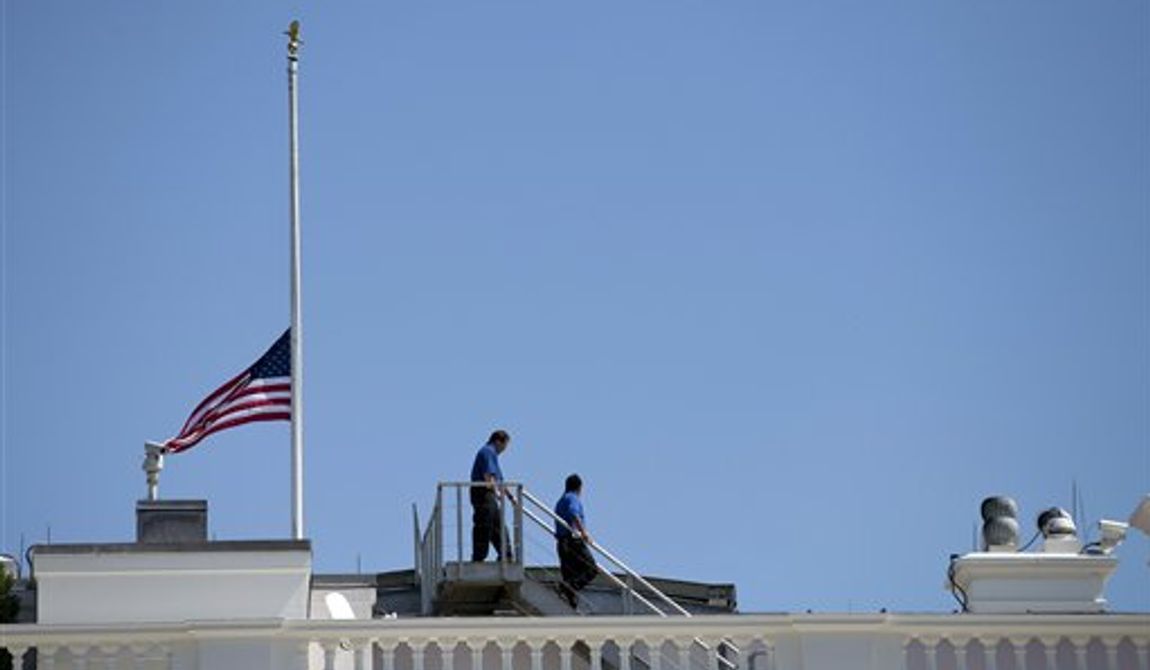 **FILE** White House workers walk on the roof of the White House on Sept. 12, 2012, after lowering the flag to half-staff for the death of U.S. ambassador to Libya Christopher Stevens. (Associated Press)