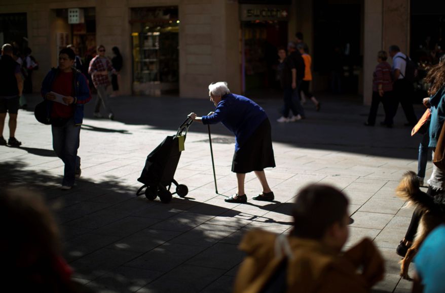 A woman pushes her shopping cart along a street in Barcelona on Tuesday, Oct. 16, 2012. Spain has raised 4.9 billion euros ($6.4 billion) at slightly lower interest rates in a debt auction that saw strong demand as the country considers whether to request international help to manage its finances. (AP Photo/Emilio Morenatti)
