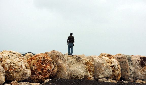 A man stands on boulders placed as a barrier to help prevent flooding of the seaside road that leads to the international airport as Hurricane Sandy approaches Kingston, Jamaica, Wednesday, Oct. 24, 2012. Hurricane Sandy pounded Jamaica with heavy rain as it headed for landfall near the country&#39;s most populous city on a track that would carry it across the Caribbean island to Cuba, and a possible threat to Florida. (AP Photo/Collin Reid)