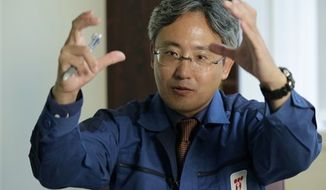 ** FILE ** In this Oct. 22, 2012 photo, Yuichi Okamura, manager of the Water Treatment System Department at the Fukushima Dai-ichi nuclear power plant, gestures while speaking during an exclusive interview at the Tokyo Electric Power Co. (TEPCO) headquarters in Tokyo. (AP Photo/Shizuo Kambayashi)

