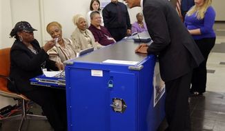 Election official Marie Holmes, left, looks over President Obama&#39;s drivers license so he can cast his vote during early voting in the 2012 election at the Martin Luther King Community Center, Thursday, Oct. 25, 2012, in Chicago. (AP Photo/Pablo Martinez Monsivais)