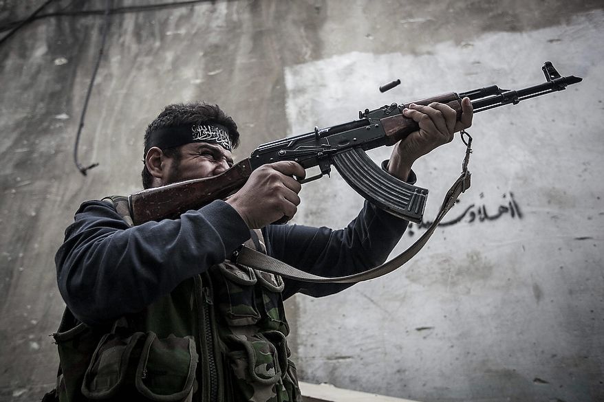 In this Wednesday, Oct. 24, 2012 photo. An Free Syrian Army fighter shoots his gun towards government troops as rebel fighters belonging to the Liwa Al Tawhid group carry out a military operation at the Moaskar front line, one of the battlefields in Karmal Jabl neighborhood, in Aleppo, Syria. (AP Photo/Narciso Contreras).