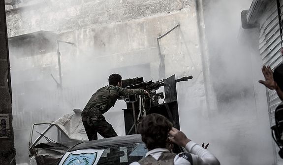In this Wednesday, Oct. 24, 2012 photo, a Free Syrian Army fighter shoots a gun as rebel fighters belonging to the Liwa Al Tawhid group carry out a military operation at the Karmal Jabl front line, in Aleppo, Syria. (AP Photo/Narciso Contreras).