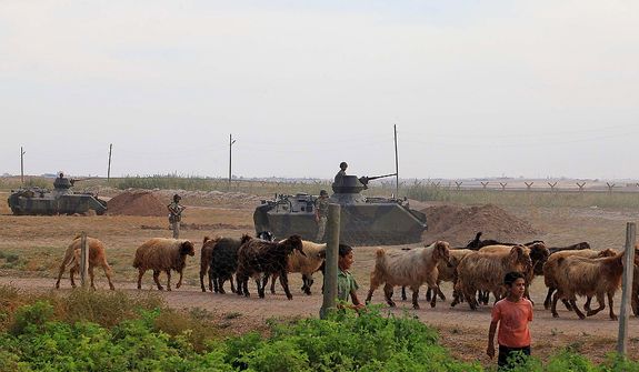A youth and goats pass by Turkish military stationed on the Turkish side of the border near Syrian rebel-controlled town of Tel Abyad, in Akcakale, Turkey, Friday, Oct. 5, 2012. Turkey&#39;s state-run news agency says Turkish troops have returned fire after a mortar shell from Syria again landed on its territory. Turkish artillery has fired at Syrian targets for two straight days after shelling from Syria killed five civilians in Turkey. .(AP Photo)