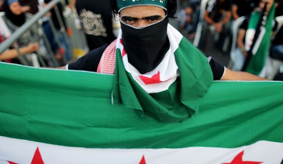 A Free Syrian Army supporter holds and covers his face with a the Syrian revolutionary flag during an anti-Syrian regime and Salafist group leader Sheikh Ahmad al-Assir demonstration in downtown of Beirut, Lebanon, Sunday, Oct. 14, 2012. Assir, a strong critic of Hezbollah leader Hasan Nasrallah and Syrian President Bashar Assad, has organized multiple protests over the past year in a bid to increase support for the Syrian uprising and mount an offensive against Nasrallah for openly supporting Assad&amp;#195;&amp;#173;s regime. Arabic writing on his headband reads, &quot;at your service God&#39;s Prophet.&quot; (AP Photo/Hassan Ammar)