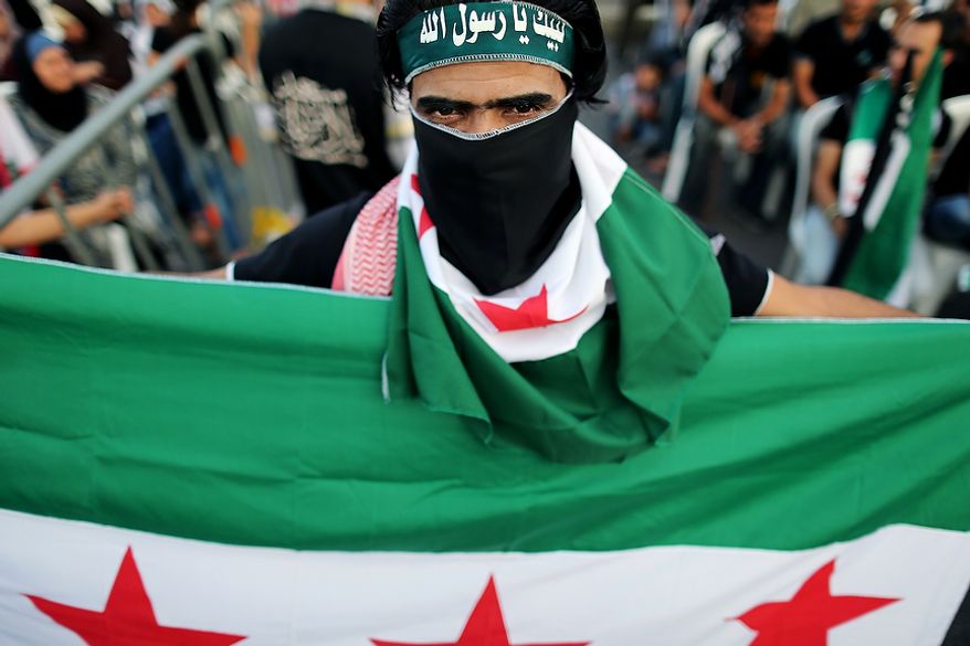 A Free Syrian Army supporter holds and covers his face with a the Syrian revolutionary flag during an anti-Syrian regime and Salafist group leader Sheikh Ahmad al-Assir demonstration in downtown of Beirut, Lebanon, Sunday, Oct. 14, 2012. Assir, a strong critic of Hezbollah leader Hasan Nasrallah and Syrian President Bashar Assad, has organized multiple protests over the past year in a bid to increase support for the Syrian uprising and mount an offensive against Nasrallah for openly supporting Assadís regime. Arabic writing on his headband reads, "at your service God's Prophet." (AP Photo/Hassan Ammar)