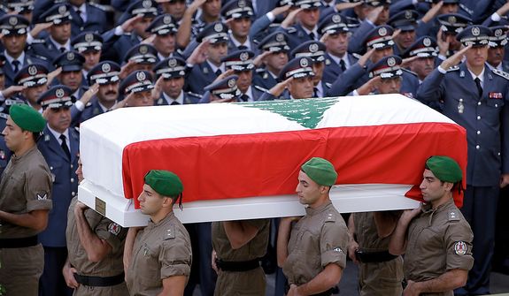 Members of Lebanese police intelligence division units, carry the coffin wrapped by Lebanese flag of Brig. Gen. Wissam al-Hassan who was assassinated on Friday by a car bomb, as police officers salute during his funeral procession at the Lebanese police headquarters in Beirut, Lebanon, Sunday Oct. 21, 2012. Thousands of Lebanese waving the national flag packed a central square in downtown Beirut Sunday for the funeral of a top intelligence official assassinated in a car bombing that many blame on the regime in neighboring Syria. (AP Photo/Hussein Malla)