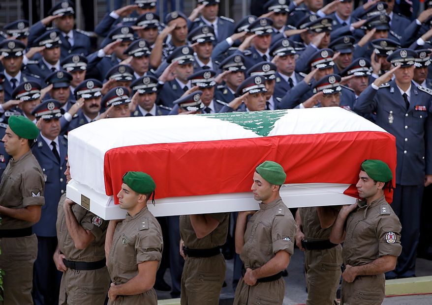 Members of Lebanese police intelligence division units, carry the coffin wrapped by Lebanese flag of Brig. Gen. Wissam al-Hassan who was assassinated on Friday by a car bomb, as police officers salute during his funeral procession at the Lebanese police headquarters in Beirut, Lebanon, Sunday Oct. 21, 2012. Thousands of Lebanese waving the national flag packed a central square in downtown Beirut Sunday for the funeral of a top intelligence official assassinated in a car bombing that many blame on the regime in neighboring Syria. (AP Photo/Hussein Malla)
