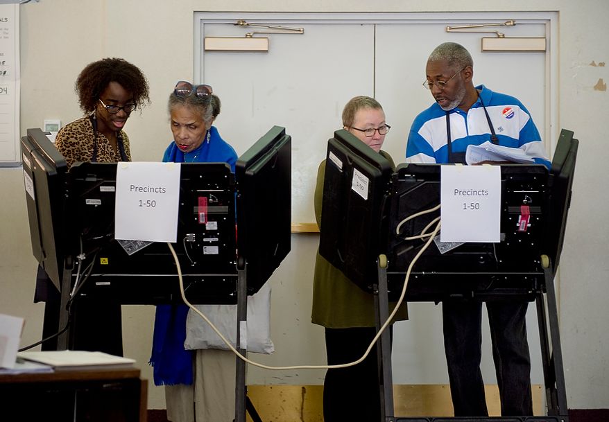 Touch-ballot clerks Stephanie Diggs (far left) and Steven Graham (far right) help voters get set up at the electronic voting booths at Judiciary Square in Washington on Wednesday, Oct. 24, 2012. According to site officials, some 2,400 people have voted here since Monday, when the voting opened. The District of Columbia will open seven more early-voting sites on Saturday (one in each ward), which will be open daily except Sundays until Nov. 3 from 8:30 a.m. to 7 p.m. (Barbara L. Salisbury/The Washington Times)