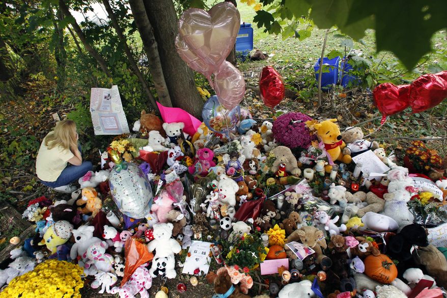 Michelle Hoffman reads a note left at a growing memorial shrine for Autumn Pasquale in Clayton,. N.J., near where the 12-year-old girl's body was found Oct. 22, 2012, in a home's recycling bin. Two teenage brothers were charged with murdering Pasquale, who had been missing since the weekend. (Associated Press)