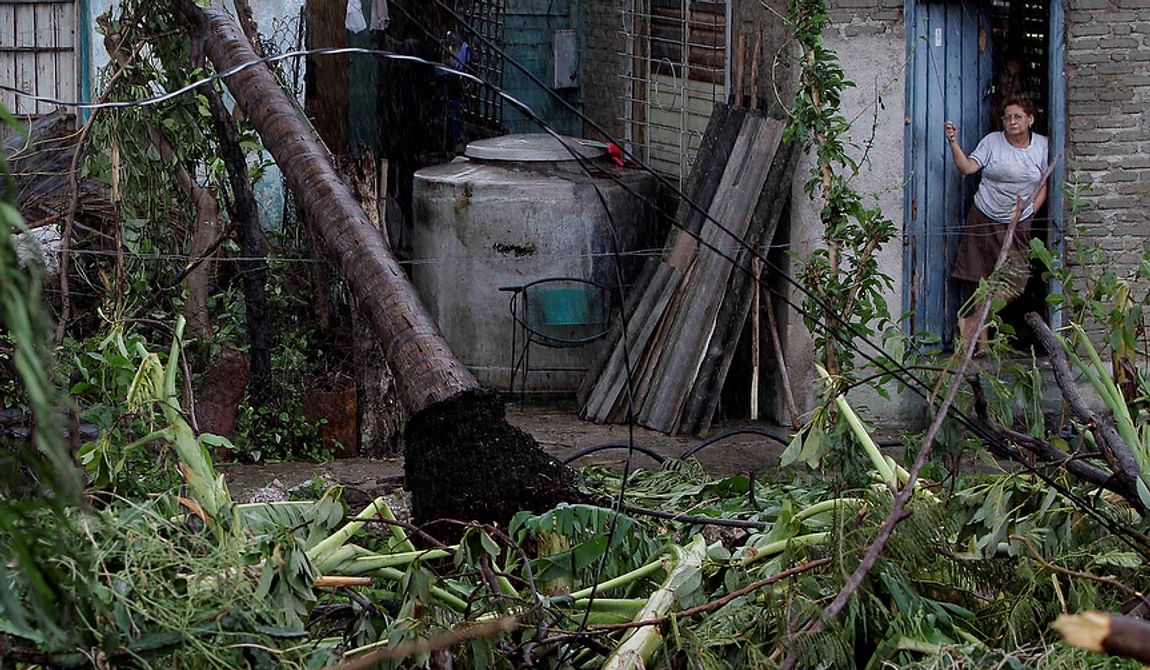 A woman stands at the entrance of her house in front of a fallen palm tree after the passing of Hurricane Sandy in Santiago de Cuba, Cuba, on Oct. 25, 2012. Hurricane Sandy blasted across eastern Cuba on Thursday as a potent Category 2 storm and headed for the Bahamas after causing at least two deaths in the Caribbean. (Associated Press)