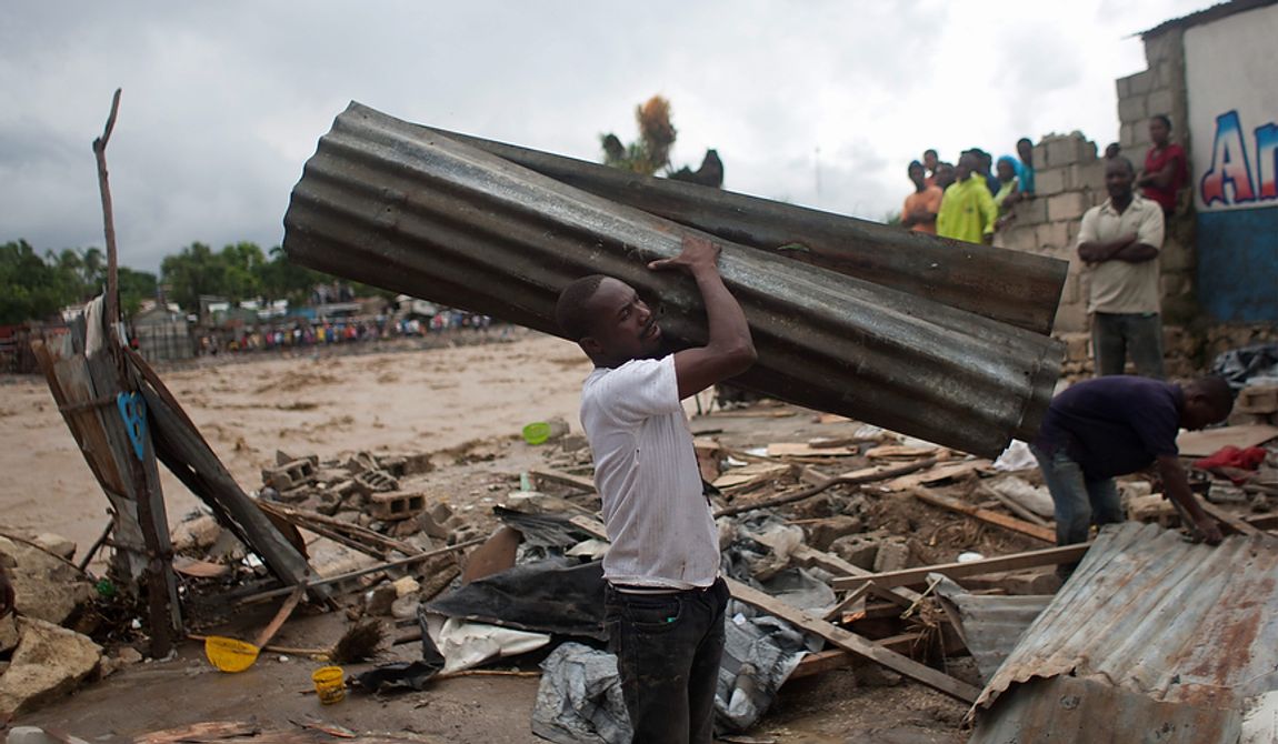 A resident carries a metal sheet, part of a damaged house after heavy rains brought by Hurricane Sandy in Port-au-Prince, Haiti, on Oct. 25,  2012. Sandy was blamed for the death of an elderly man in Jamaica who was crushed by a boulder. Another man and two women died while trying to cross storm-swollen rivers in southwestern Haiti. (Associated Press)