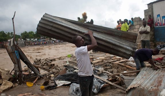 A resident carries a metal sheet, part of a damaged house after heavy rains brought by Hurricane Sandy in Port-au-Prince, Haiti, on Oct. 25,  2012. Sandy was blamed for the death of an elderly man in Jamaica who was crushed by a boulder. Another man and two women died while trying to cross storm-swollen rivers in southwestern Haiti. (Associated Press)