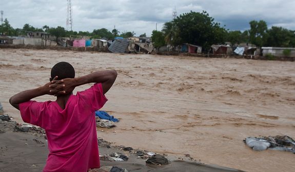A man watches a river affected by heavy rains brought by Hurricane Sandy in Port-au-Prince, Haiti, on Oct. 25,  2012. Sandy was blamed for the death of an elderly man in Jamaica who was crushed by a boulder. Another man and two women died while trying to cross storm-swollen rivers in southwestern Haiti. (Associated Press)