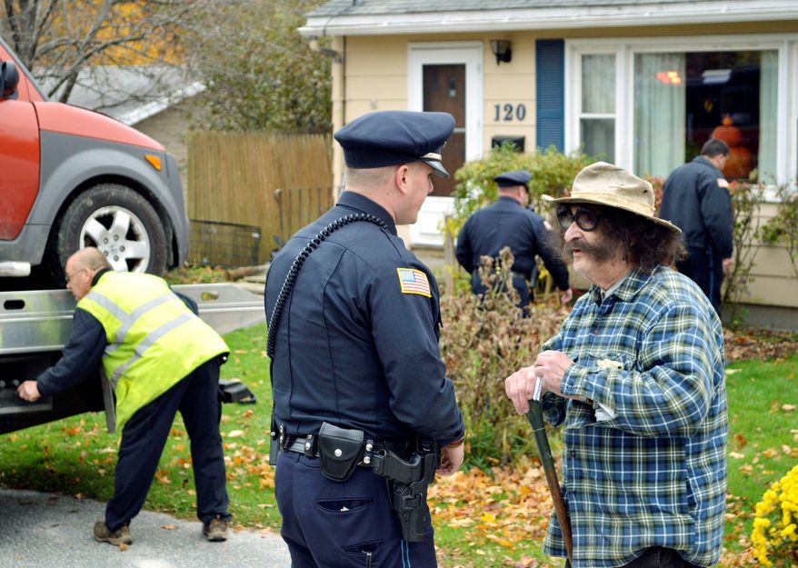 Movie critic Gene Shalit talks with a Lenox, Mass., police officer after crashing his car into a house on Wednesday. Mr. Shalit, 86, faces a misdemeanor charge. (The Berkshire Eagle via Associated Press)