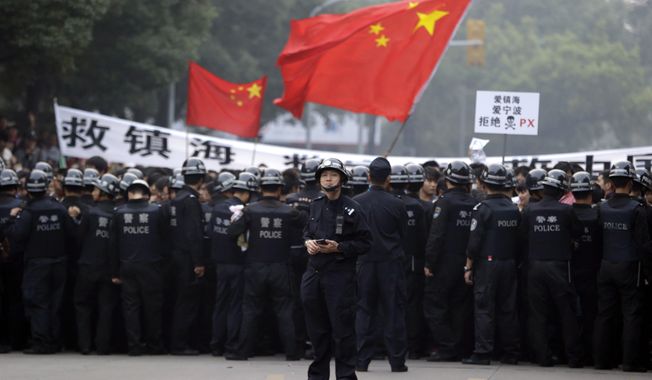 A Chinese policeman stands in front of fellow officers confronting residents who gathered outside the government office in Zhejiang province&#x27;s Ningbo city on Sunday, Oct. 28, 2012, to protest the proposed expansion of a petrochemical factory. (AP Photo/Ng Han Guan)

