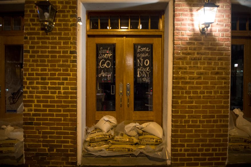 A message is written on the doors of The Lucky Knot on King Street during high tide, as a little flooding occurs along the waterfront in Old Town Alexandria, Va., Sunday, Oct. 28, 2012 while Hurricane Sandy makes it's way north along the Atlantic coast. (Rod Lamkey Jr./The Washington Times)