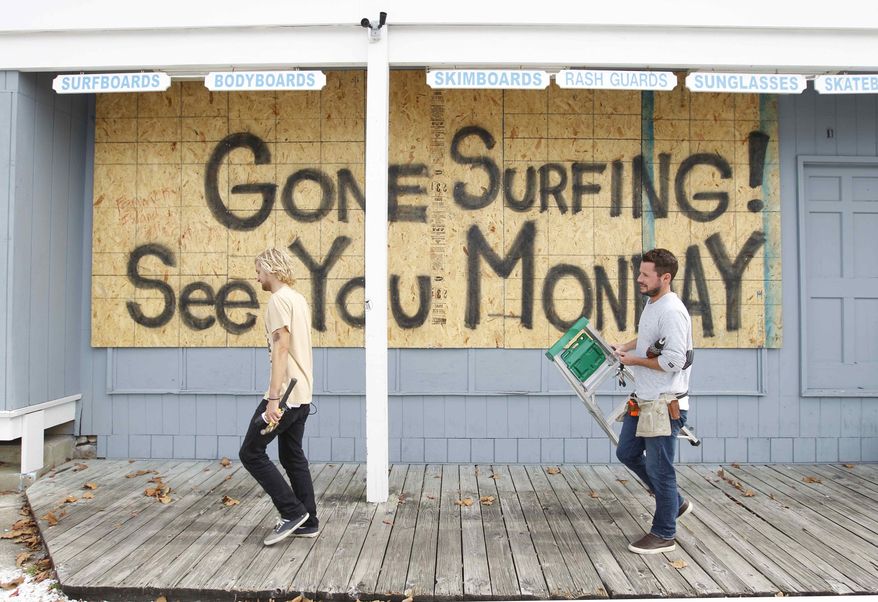 Store workers Fletcher Birch, right, and Jay Kleman finish boarding up the windows on a surf store in Ocean City, Md., on Saturday, Oct. 27, 2012, as Hurricane Sandy approaches the Atlantic coast. (AP Photo/Jose Luis Magana)