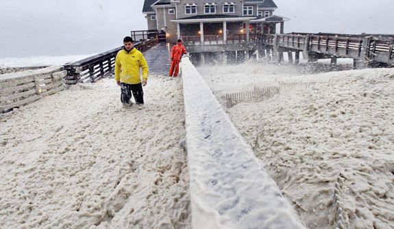 A news crew wades through sea foam blown onto Jeanette&#39;s Pier in Nags Head, N.C., Sunday, Oct. 28, 2012 as wind and rain from Hurricane Sandy move into the area.  Governors from North Carolina, where steady rains were whipped by gusting winds Saturday night, to Connecticut declared states of emergency. Delaware ordered mandatory evacuations for coastal communities by 8 p.m. Sunday. (AP Photo/Gerry Broome)