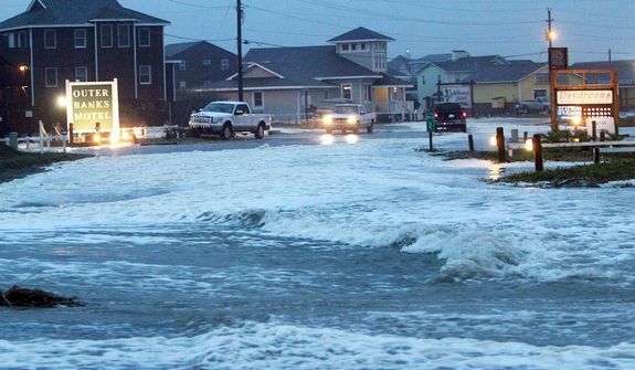 Ocean water rolls over NC 12 at the north end of Buxton, N.C. at dawn on Sunday, Oct. 28, 2012. Waves from offshore Hurricane Sandy are battering Hatteras Island. (AP Photo/The Virginian-Pilot, Steve Earley)